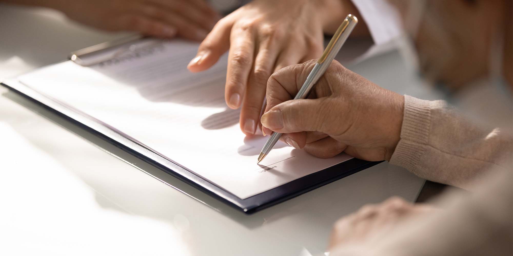 Manos firmando un contrato de seguro con asesoría profesional