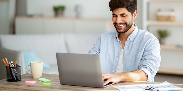 Hombre joven trabajando en su computadora portátil desde casa