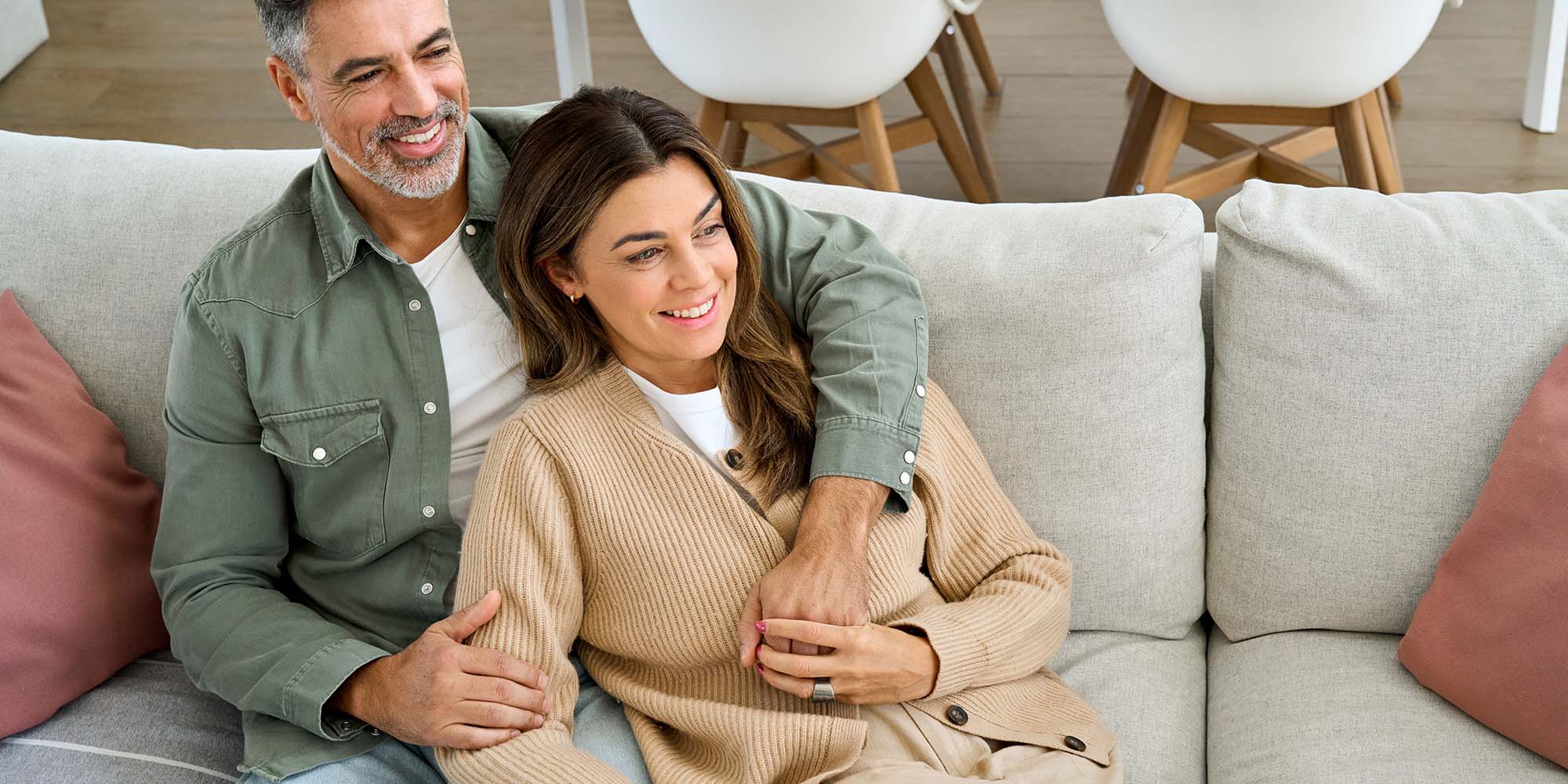 Pareja sonriente abrazada en el sofá